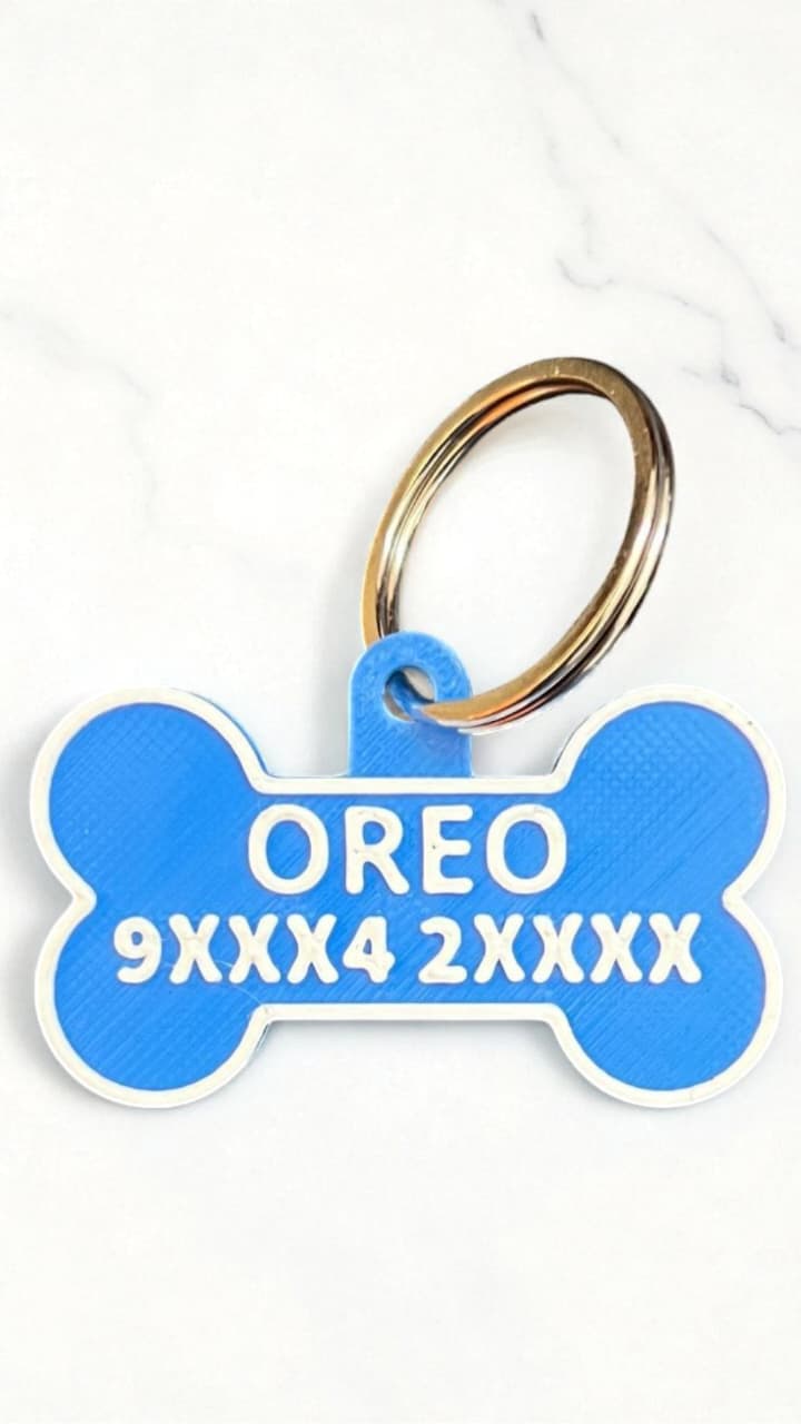Blue bone-shaped pet tag with 'OREO' and identification numbers on a white background